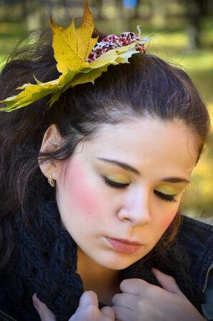 Young sad woman with bright makeup and with leaves ih her hairの写真素材