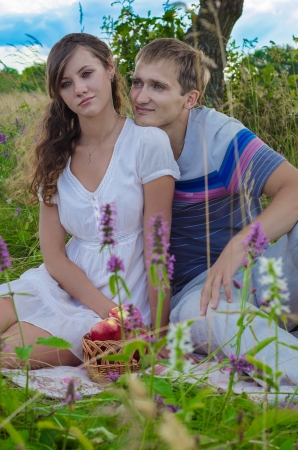 Young couple with a basket of apples relaxing outdoorsの写真素材