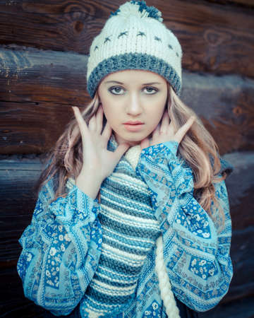 Portrait of a young attractive girl in a vintage style wearing knitted hat and shawl walking in the countrysideの写真素材