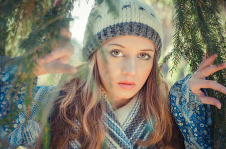 Portrait of a young attractive girl in a vintage style wearing knitted hat and shawl walking in the...