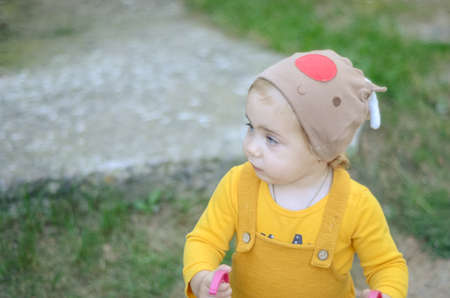 Photo of a toddler girl in the funny hat playing with a toy strollerの写真素材