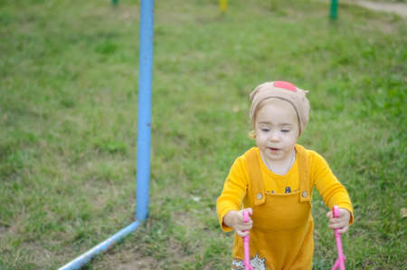 Photo of a toddler girl in the funny hat playing with a toy strollerの写真素材