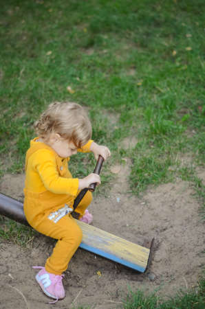 Photo of a blue-eyed toddler girl playing outside on the playgroundの写真素材