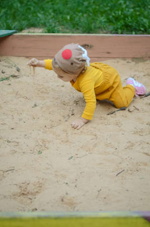 Photo of a blue-eyed toddler girl playing outside with sandの写真素材