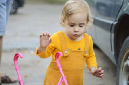 Photo of a toddler girl in the funny hat playing with a toy strollerの写真素材
