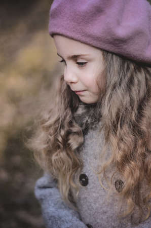 Picture of a vintage styled little girl in a beret and coat walking in the forestの写真素材