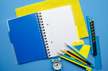 Flatlay empty space dark blue cover notebook spring with blank pages strip , blank blue and yellow blue alarm clock, black pencils , central compositionの写真素材