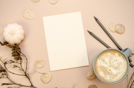 Autumn minimal postcard card invitation muckup with latte on tan begie horizontal background with dry brown branches, transparent petals and white pumpkin candle.の写真素材