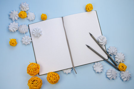 Top view flat lay macarons Opened blank notebook mockup blank pages, dark pencils and yellow decor blue background Template winter composition for new year plan wish list, to do list, winter recipesの写真素材