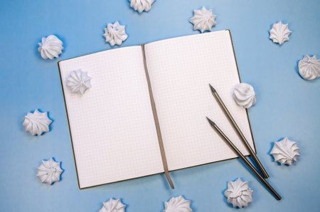 Top view flat lay Frame macarons cookies Opened blank notebook mockup blank pages, dark pencils - blue background Template winter composition for new year plan wish list, to do list, winter recipesの写真素材