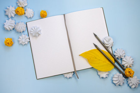 Top view flat lay macarons Opened blank notebook mockup blank pages, dark pencils and yellow decor blue background Template winter composition for new year plan wish list, to do list, winter recipesの写真素材