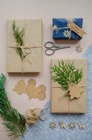 Hand crafted gifts on dark background with Christmas decorations. Seasonal background shot from above. Flat lay, top view. Tag mockup, copy space on the tags.の写真素材