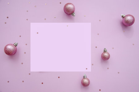 Mock up with square invitation card on trendy pastel light pink background with christmas ornaments. Greeting card and silver Christmas baubles. Minimal christmas concept.の写真素材