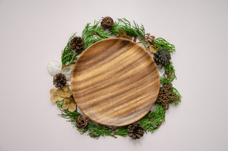 Christmas and new year festive card template on wooden plate with dried flowers, thuja branches, thuja buds and fir cones, flat lay, top viewの写真素材