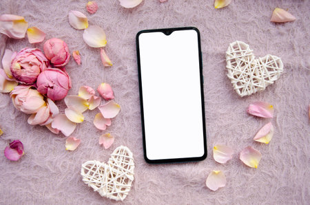 Digital smartphone, blank screen with small petals and white tangled hearts on pink knitted background.Valentines Day background and Copy space for your text.の写真素材