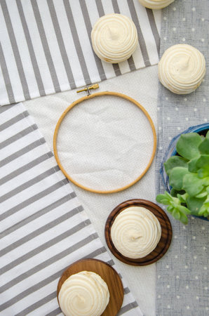 Meringue homemade zephyr marshmallows with round embroidery hoop frame, and echeveria plant on cotton tablecloth. mockup card. Template for recipes, food menu, craftの写真素材