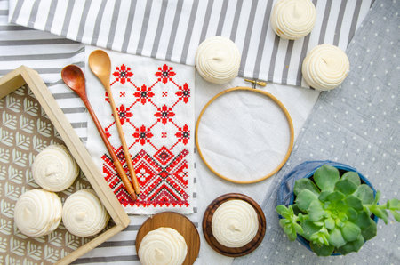 Round hoop frame, wooden spoons, meringue homemade zephyr in wooden tray, embroided napkin with traditional ornament and echeveria plant. mockup card. Template for recipes, food menu, craftの写真素材