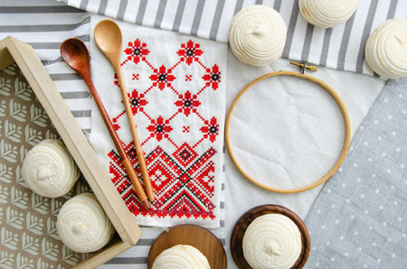 Round hoop frame, wooden spoons, meringue homemade zephyr in wooden tray and embroided napkin with traditional ornament. mockup card. Template for recipes, food menu, craftの写真素材