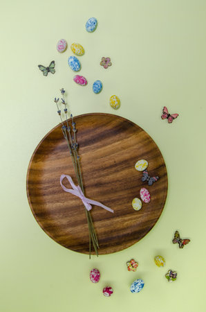 Egg shape candies, wooden plate, dried lavender on neutral background, Easter holiday sweets and decor.の写真素材