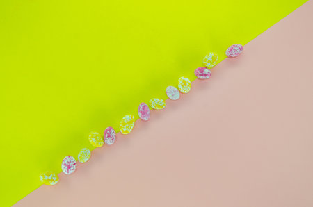 Little candy eggs on a pink-yellow background. Horizontal top-view layout for Easter
