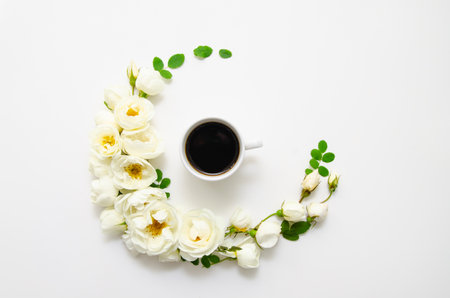 A cup of coffee, composition of white roses, green leaves and petals. Mother's day card, valentine's day.の写真素材