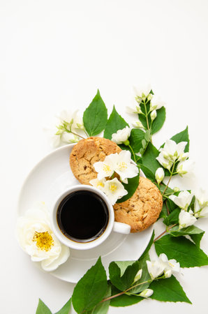 A cup of coffee, white saucer, oatmeal cookies, white roses and jasmine flowers. Mother's day card, valentine's day.の写真素材