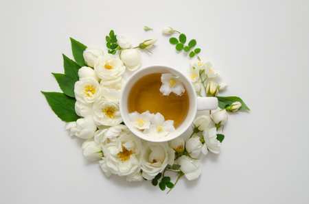 A cup of jasmine tea, wreath of white roses and petals, jasmine flowers and leaves. Mother's day card, valentine's day.の写真素材