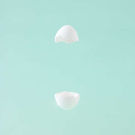 Easter white flying egg shell on the pastel green background with a creative space. Minimal concept.