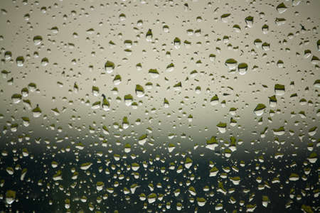 Water drops on a window photographed on a rainy day. These raindrops simply look magical.の写真素材