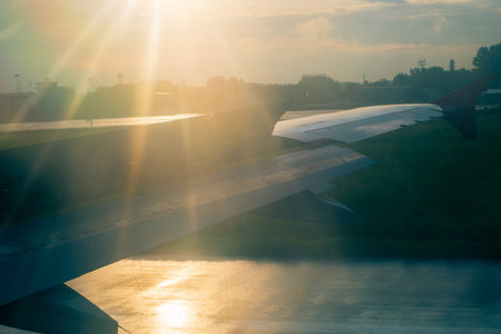 Aircraft wing in Sun rays at landing. Early morning.