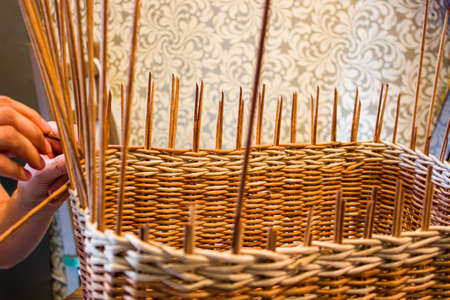 A woman weaves a basket from a paper vine. The hands of the master are shown.の写真素材