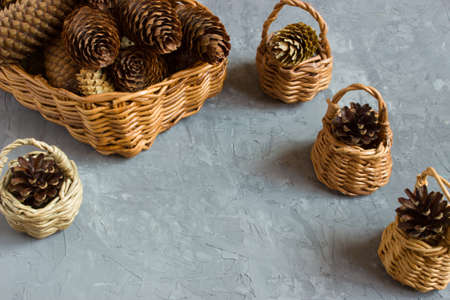 Cones lying in wicker baskets of different shapes and sizes on a gray concrete backgroundの写真素材