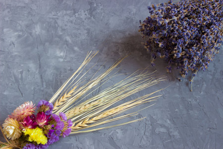 Dried multicolored flowers with ears of wheat and lavender lie on a concrete backgroundの写真素材