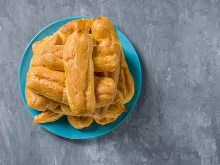 Stack of Eclairs on a blue plate on a gray background.