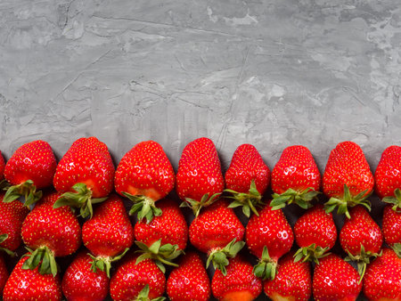 Fresh juicy ripe strawberry with leaves on a gray background.