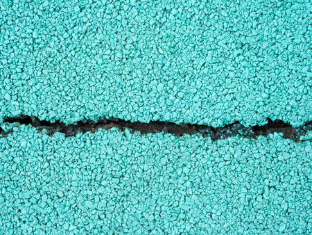 Flexible turquoise tile for playground with a crack in the middle. Tiles made from a mixture of...
