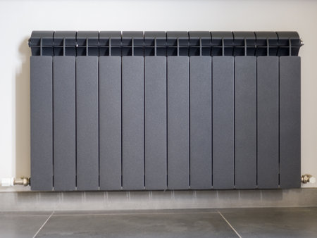 Black aluminum radiator for water heating on the wall in a private house.の写真素材