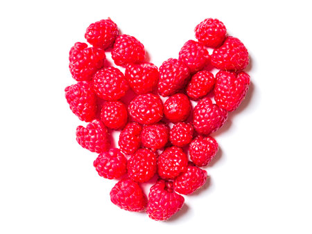 Close-up of fresh ripe raspberries laid out in the shape of a heart.