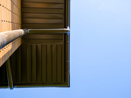 Bottom view of the roof of a house with a storm drain and the blue sky.