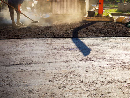 Laying new asphalt. The process of leveling the asphalt manually using a special rake.の写真素材
