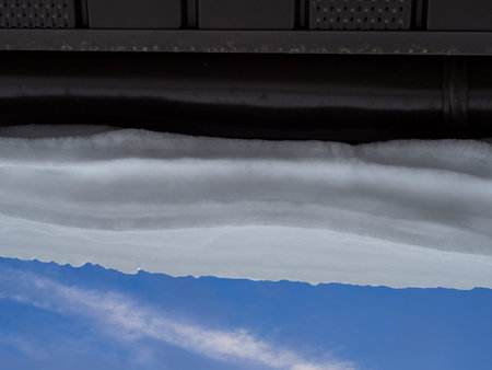 Snow hanging on the roof drainpipe. The drainpipe are covered with snow.