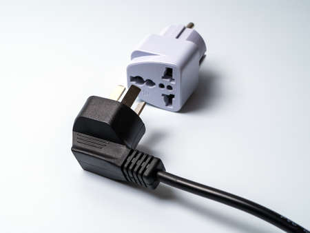 An electrical plug lying next to an adapter for another type of electrical plug. Ready to connect.の写真素材