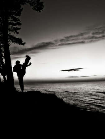 Active man training martial arts near the beach. Kicking high in the sky.の写真素材