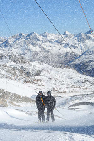 T bar ski lift pulling two skiers up the slope. Beautiful mountain landscape.. Snowy winter in European Alps.の写真素材
