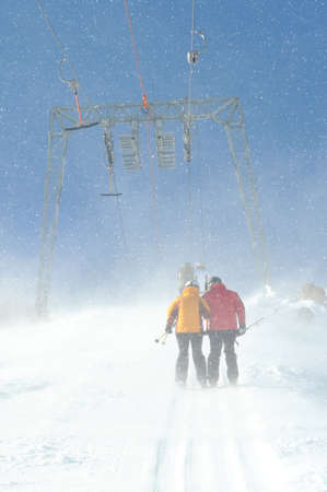T bar ski lift pulling couple of skiers up the slope. Snowy winter in European Alps.の写真素材