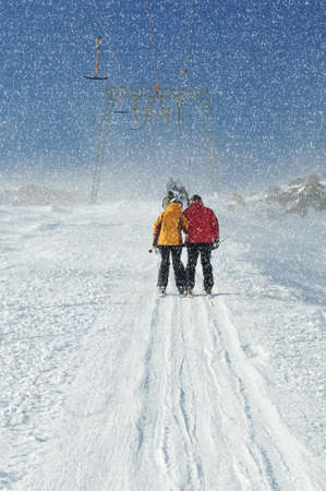 T bar ski lift pulling couple of skiers up the slope. Snowy winter in European Alps.の写真素材