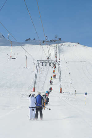 T bar ski lift pulling skiers up the slope. Wide ski slopes on left and right.の写真素材