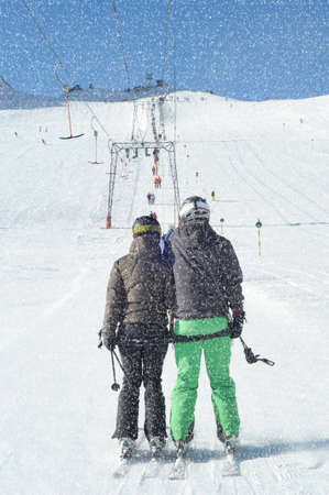 T bar ski lift pulling couple of skiers up the slope. Snowy winter in European Alps.の写真素材