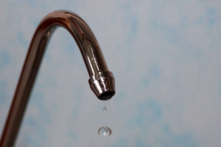 kitchen tap with water drops on a light-blue backgroundの写真素材