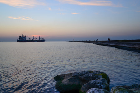sunset at pier and a passing shipの写真素材